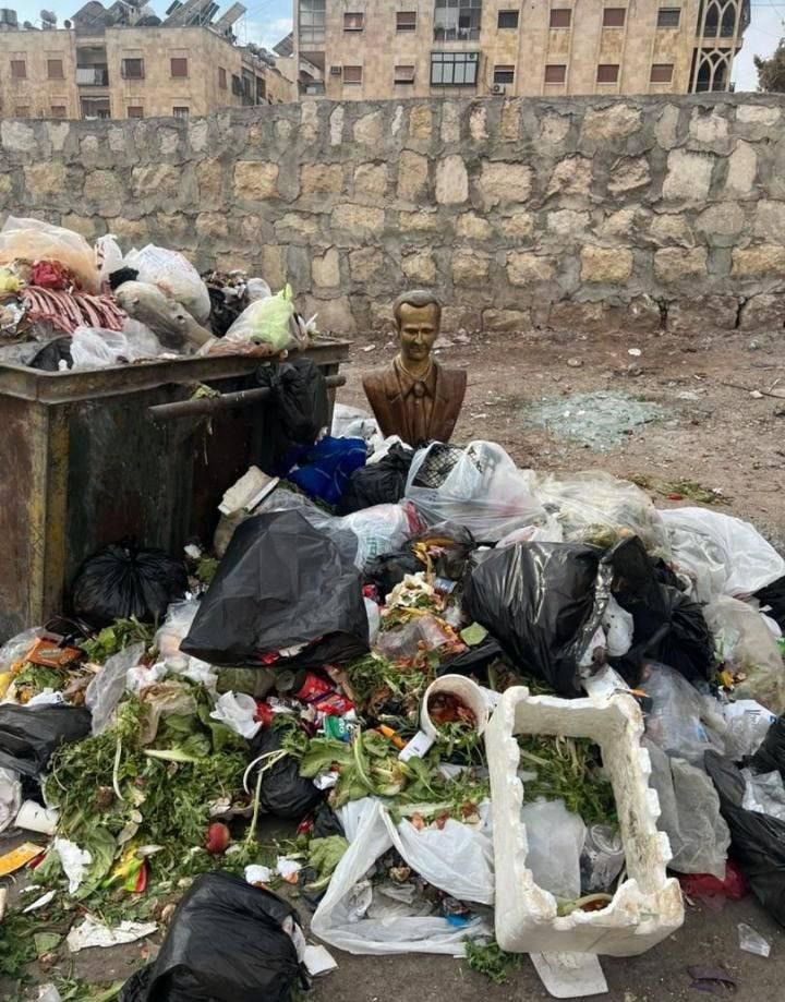 Un busto di Assad padre vicino a un bidone dell'immondizia, in mezzo ai rifiuti, ovvero dove deve stare